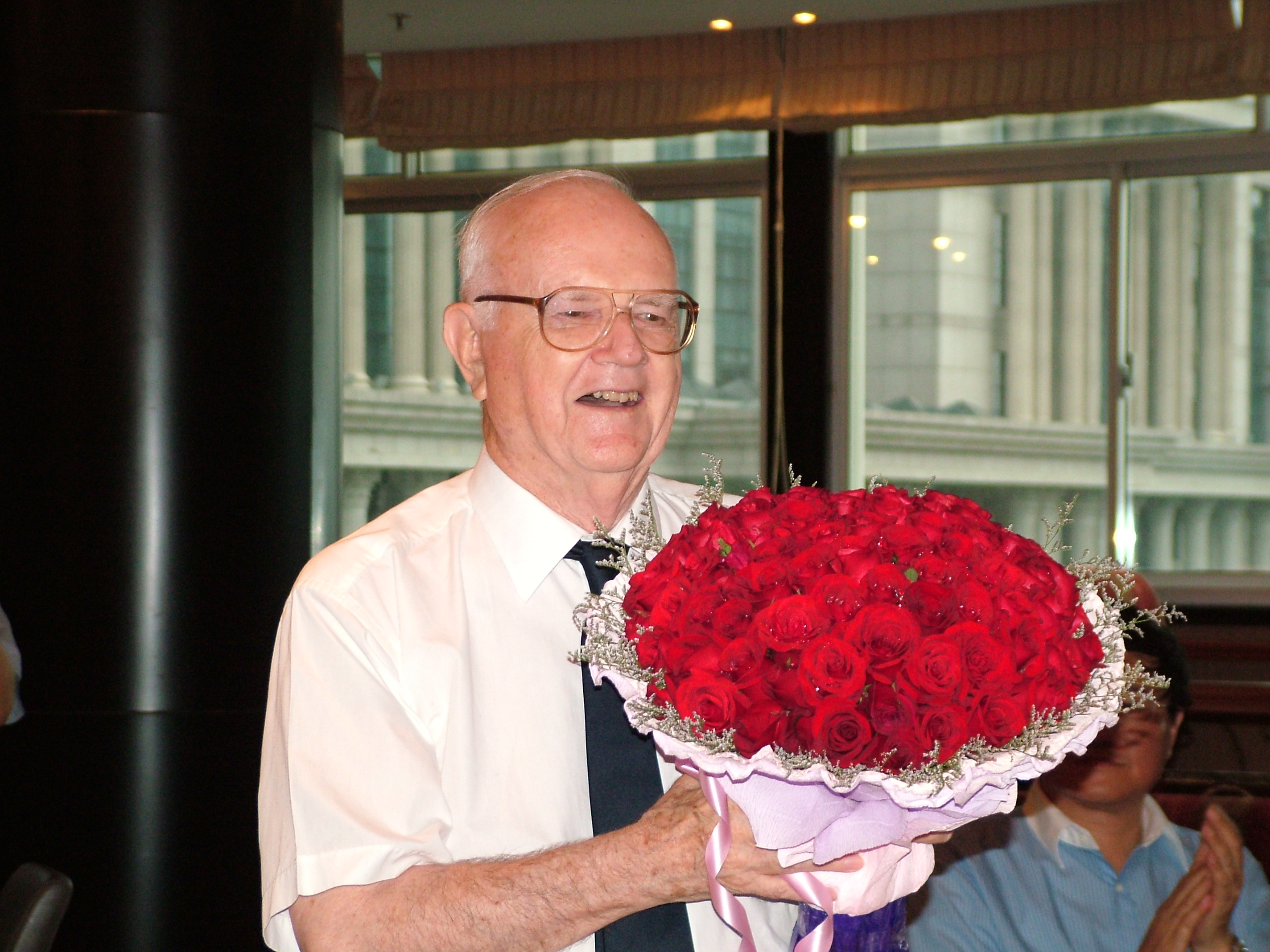 Father George McLean beaming with immense gratitude while receiving 80 red roses on his eightieth birthday