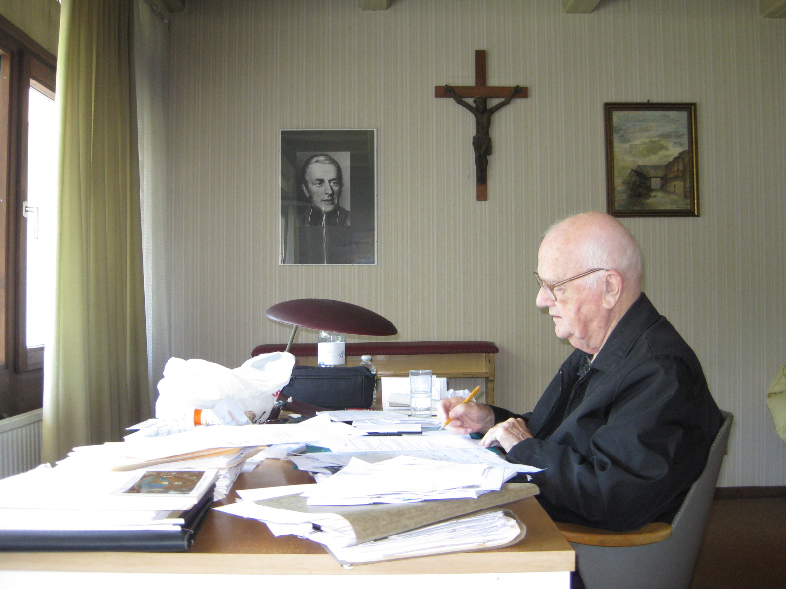 Father McLean at his scholarly study desk in Vienna with manuscripts, crucifix, and portrait of St. Eugene de Mazenod